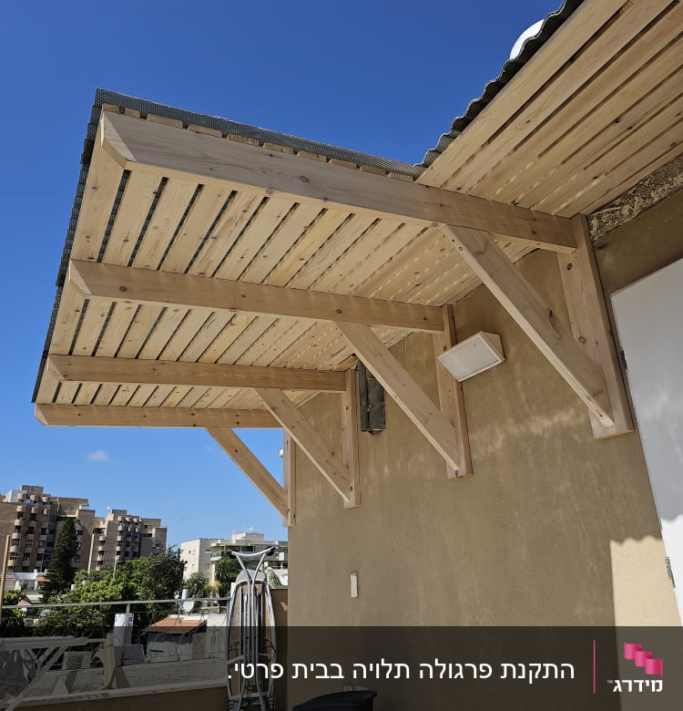 פרגולה מעץ מחוברת לקיר חיצוני של מבנה